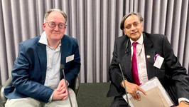 A photo of Gideon Rachman and Shashi Tharoor sitting on chairs on a stage at the Mortimer Dialogue.