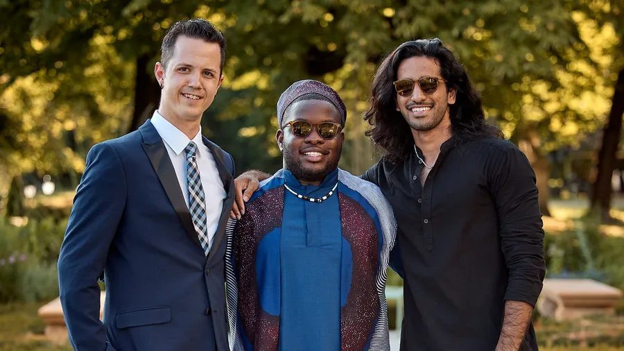 A group of three young men smiling at the camera with arms around each other