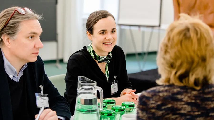 Three Salzburg Global Fellows from Bridging Worlds: How Can We Use Business and Economic Development Strategies to Support Better Health? chat together around a table in Parker Hall
