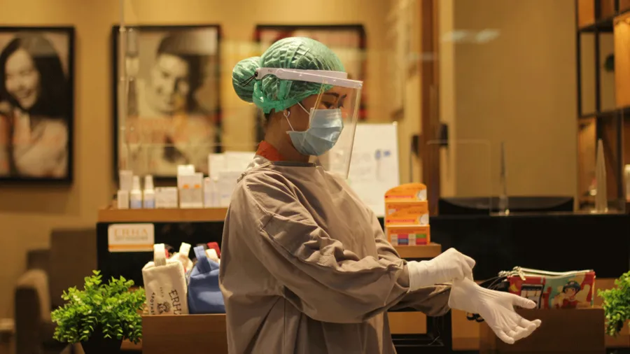 Woman in protective gear putting on surgical gloves