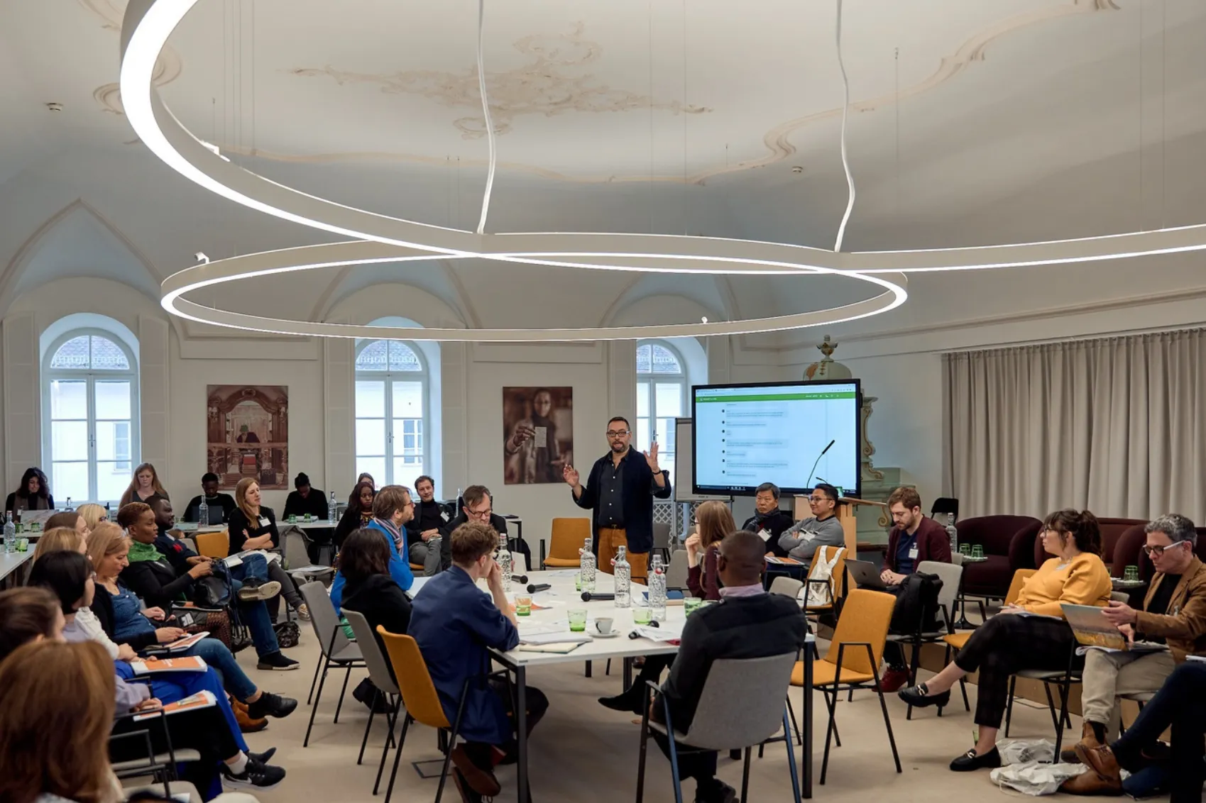 A Presentation With a Digital Screen With a Group of People Sitting Inside the Schloss