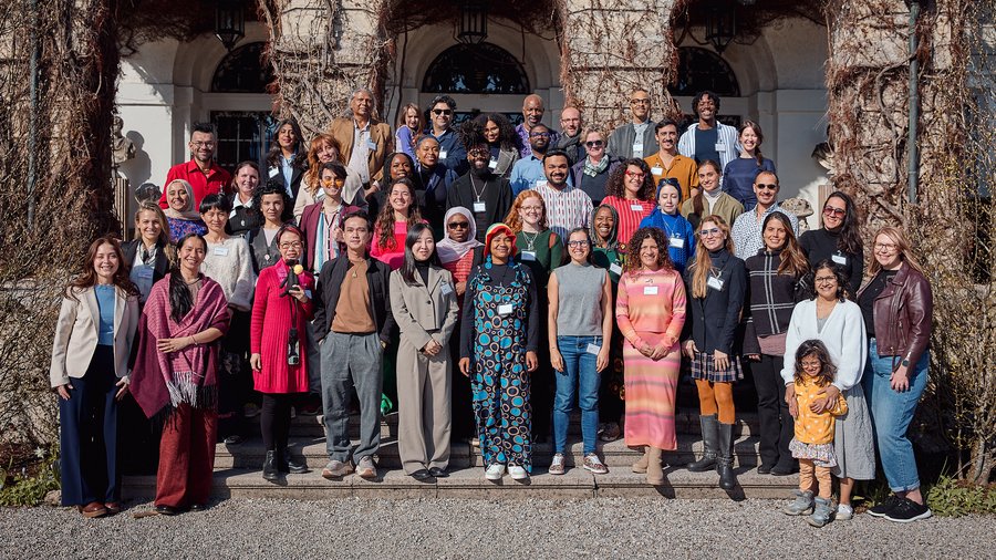 A group of individuals standing on the steps of Schloss Leopoldskron and smiling into the camera