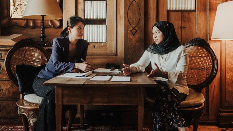 Two women engaged in a collaborative discussion while seated at a table in the Max Reinhardt Library of Schloss Leopoldskron.