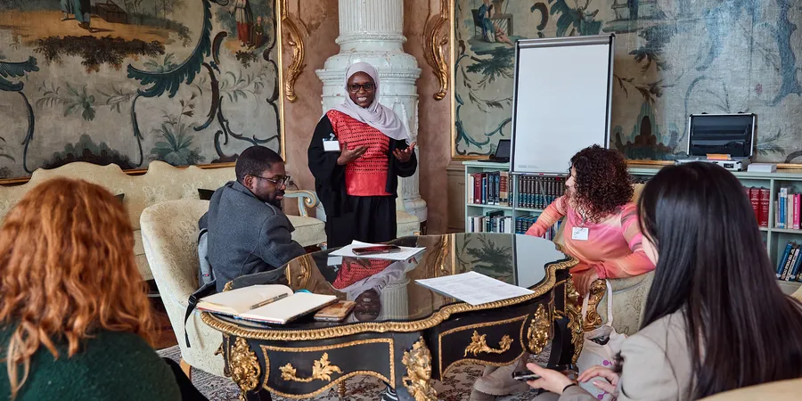 A woman speaks to a group of people in the Green Salon of Schloss Leopoldskron