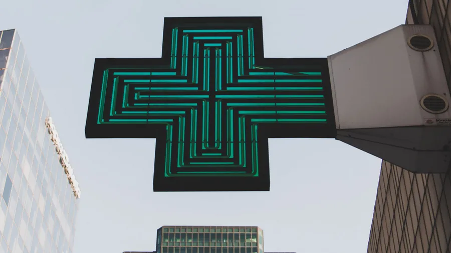 A green cross sign in a business district - Photo by Justin Chrn on Unsplash