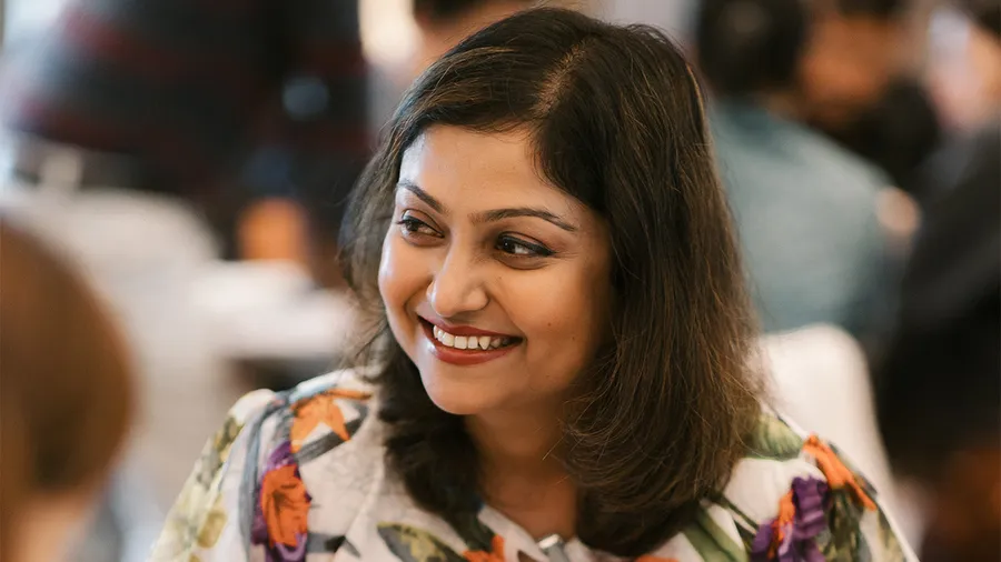 a woman with dark hair looks to the left and smiles