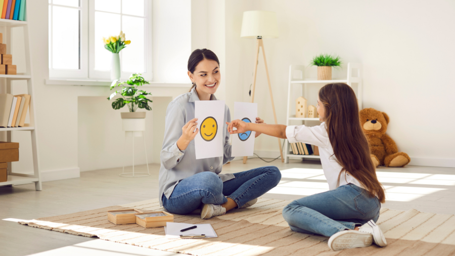 a woman teaches a young girl about emotions with a picture of a smiley