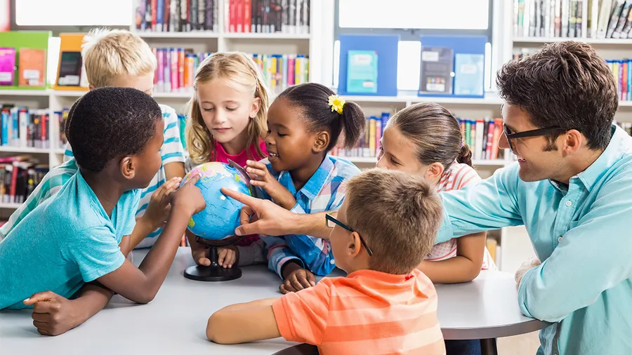 a group of young students gathered around a globe with a teacher
