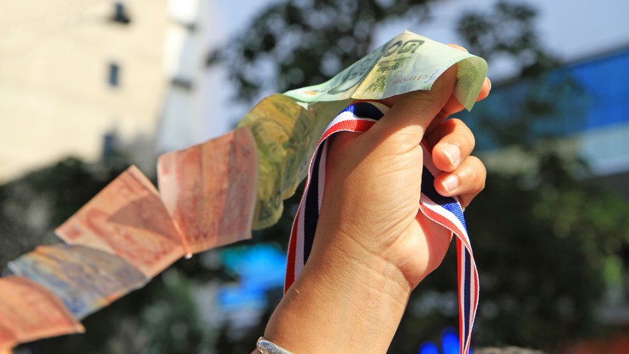 A hand holds a ribbon with the Thai colors and a string of money on February 7,2014 in Bangkok, Thailand. 