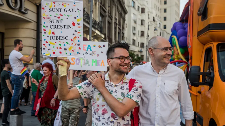 Salzburg Global Fellow Victor Ciobotaru and his life partner Florin at the Bucharest Pride in July 2019 holding a poster with the message: “Sunt gay, Sunt Crestin, Iubesc.” – “I am gay. I am a Christian. I Love.” – Photo Credit: Ioana Moldovan