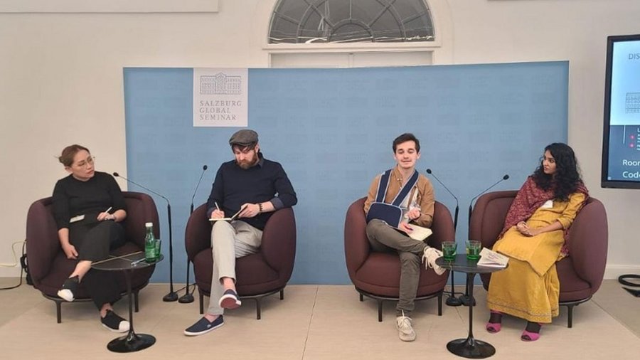 Four people sit on a stage, each person with a microphone. They are in the middle of a discussion.                                                                                                                                                                                                                                                                                                                                                                                                                                                                                                                                                                                                                                                                                                                                                                                                                                                                                                                                                                                                                                                                                                                                                                                                                                                                                                                                                                                                                                                                                                                                                                                                                                                                                                                                                                                                                                                                                                                                                                                                                                                                                                                                                                                                                                                                                                                                                                                                                                                                                         