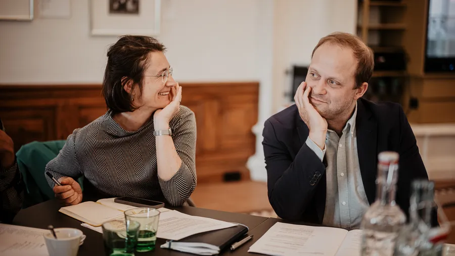 a woman and a man sitting smiling at a table in the Gallery of Schloss Leopoldskron