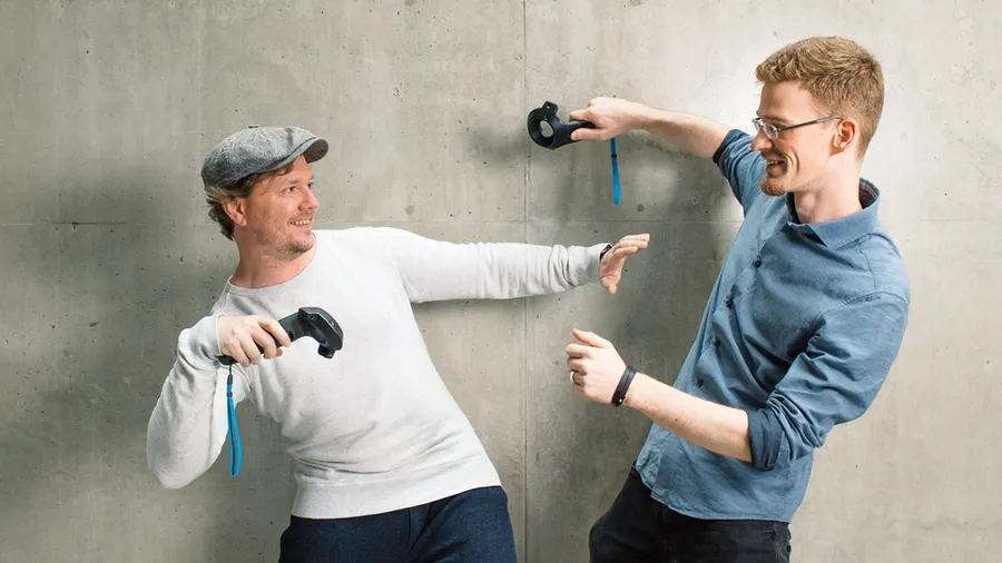Robert Praxmarer and Thomas Layer-Wagner smiling in an action pose with some game controllers.