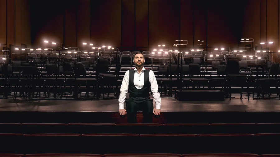 Paolo Petrocelli seated on stage gazing upwards at the Dubai Opera