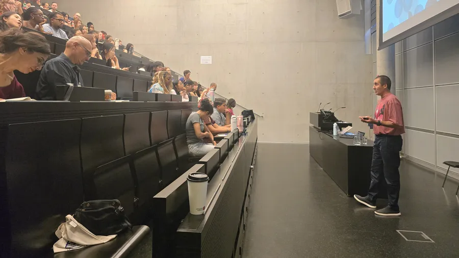 a man stands in front of a lecture hall filled with students