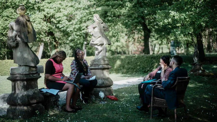 A group of Salzburg Global Fellows sitting in the garden of Schloss Leopoldskron during having a discussion during the Africa Forum
