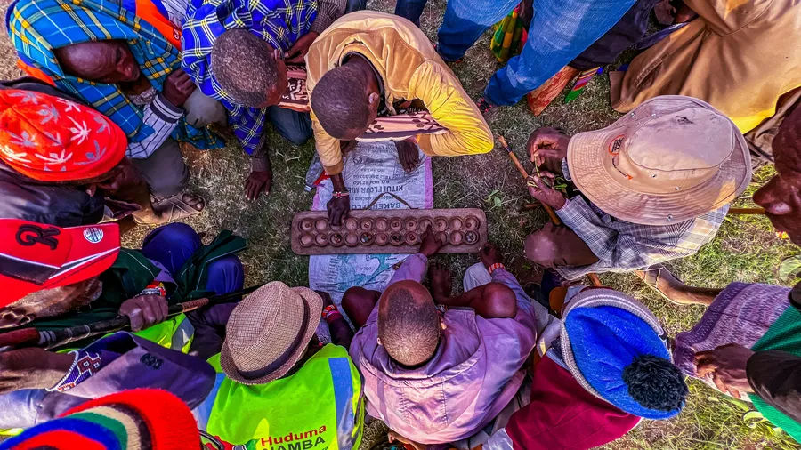 a group of people gather together in Samburu, Kenya around an object in the middle, with their hands looking down at it.