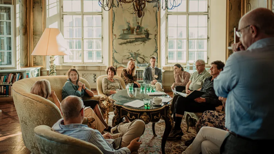 A group of people sit in a circle engaging in a conversation 