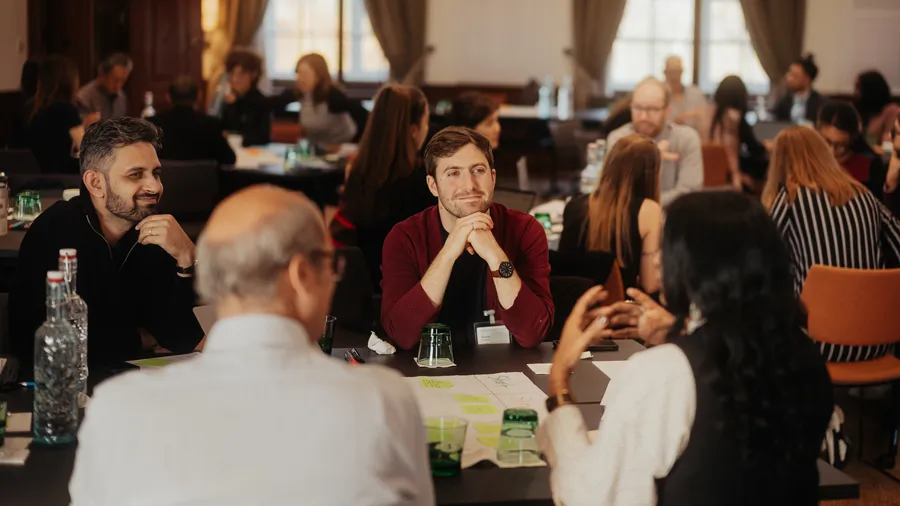 a group of people sit engaged in a discussion in the Gallery of Schloss Leopoldskron