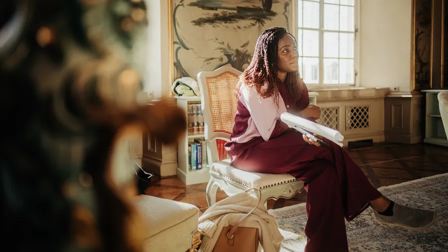 a woman sits with her legs crossed and looks to the right in the Green Salon of Schloss Leopoldskron