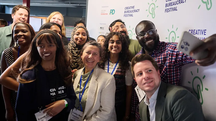 a group of Fellows pose for a selfie in front of a branded backdrop
