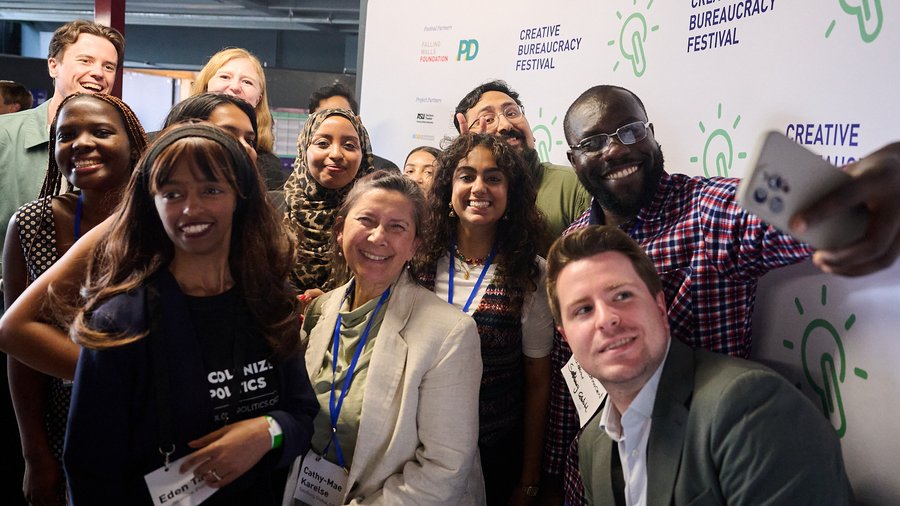 a group of Fellows pose for a selfie in front of a branded backdrop