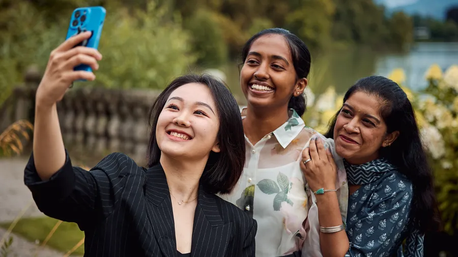 Three women take a selfie and smile at a phone camera