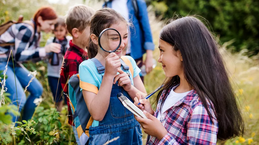 Group of school children with teacher on field trip in nature, learning science.