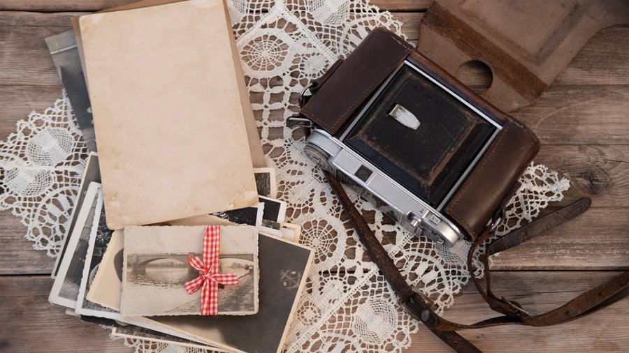 Antique black and white photos laying on a table next to an old camera