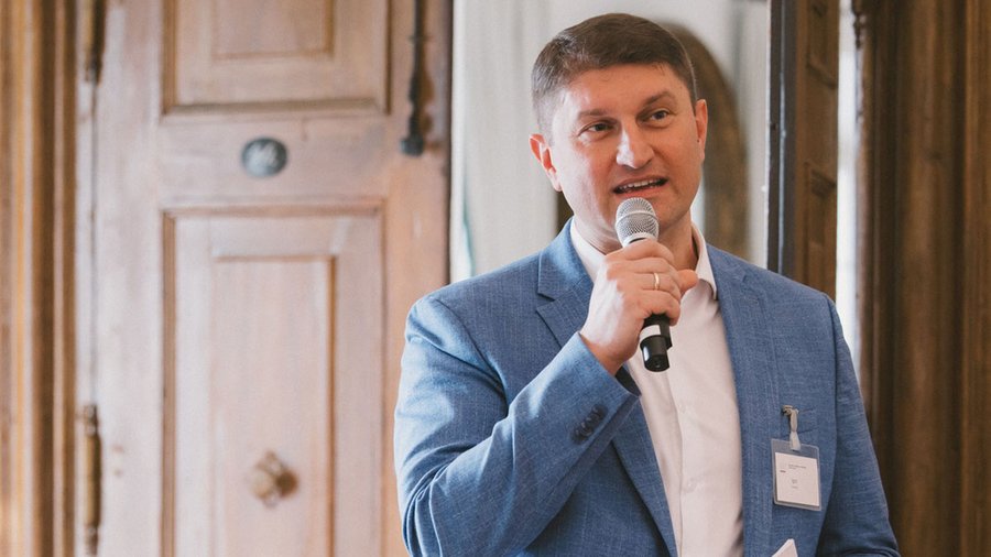 a man with light hair speaks into a microphone