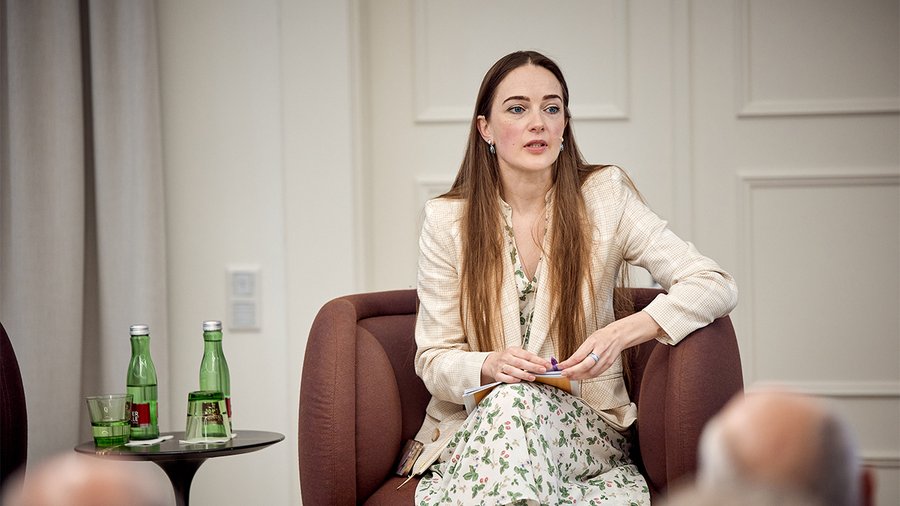 A women named Oleksandra Matviichuk sits in front of an audience delivering a speech