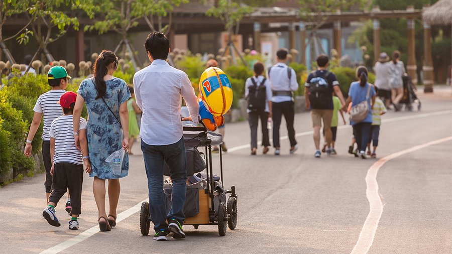 a few families walk through a park and we see them from behind