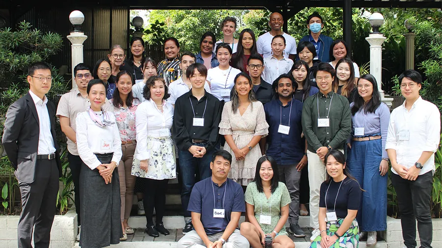 Group photo of around 30 CMP participants standing together outside on stairs and smiling at the camera.