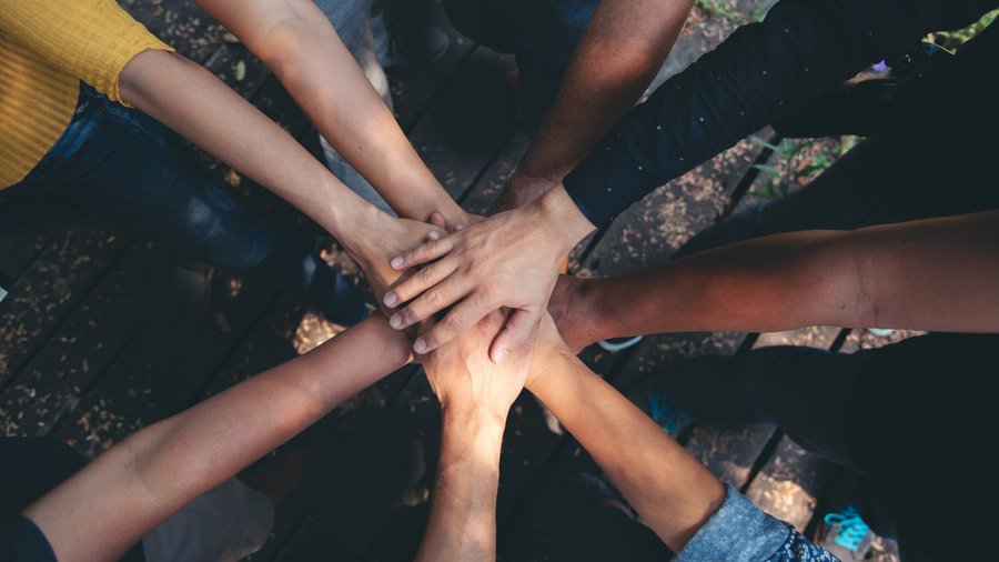 A group of diverse hands coming together, showcasing unity and belonging.