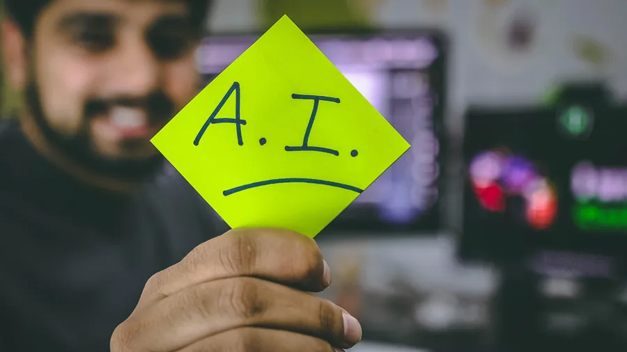 Photo of a man holding a post-it note that says AI