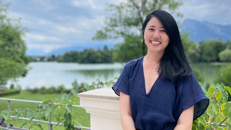 A woman sits smiling and looking to the left
