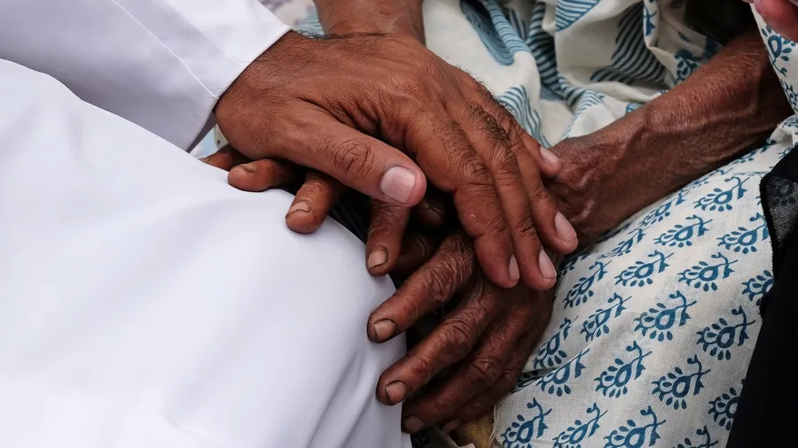 Hands, young and old, on top of each other, comforting each other in Kumrokhali, West Bengal, India