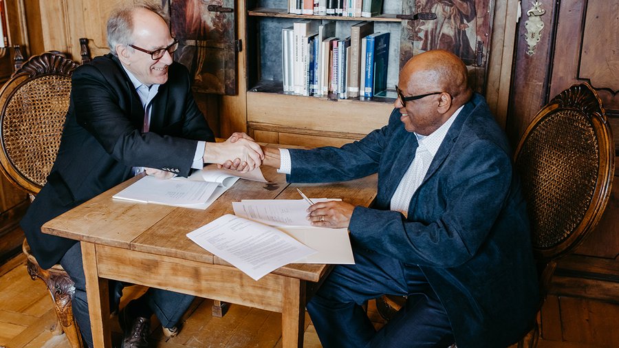 Salzburg Global President Stephen L. Salyer and ETS Vice President Michael T. Nettles shake hands after signing new three-year partnership agreement