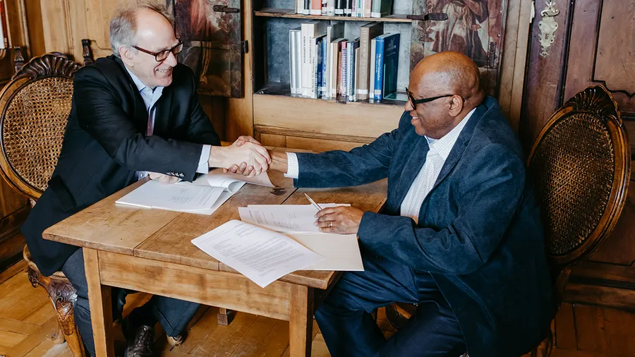 Salzburg Global President Stephen L. Salyer and ETS Vice President Michael T. Nettles shake hands after signing new three-year partnership agreement
