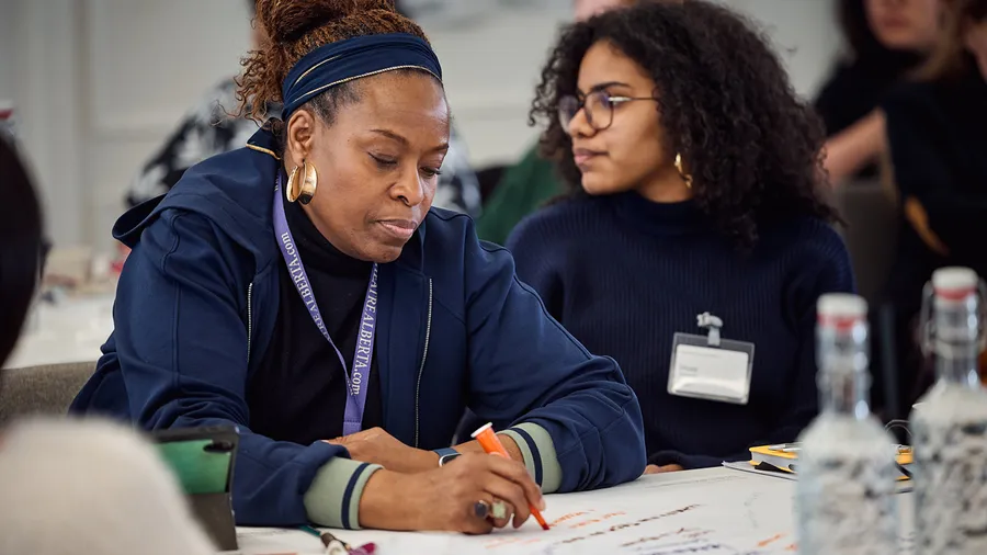 This photo shows Nike Jonah writing on a piece of paper during the Culture, Arts and Society session, "Creating Futures: Art of Narrative"
