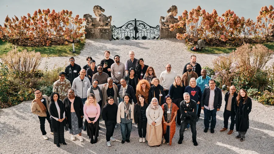 A group of individuals stand together smiling outside Schloss Leopoldskron.