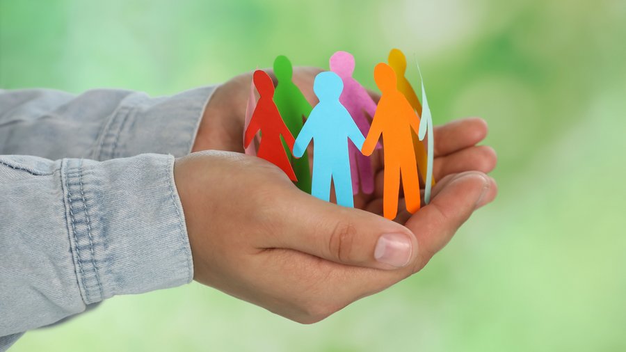 Woman holding paper human figures on blurred green background