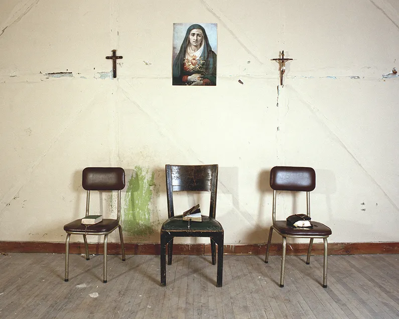 Three Chairs in Front of a Wall with Two cruzifixes and a Mother Maria Image in The Middle