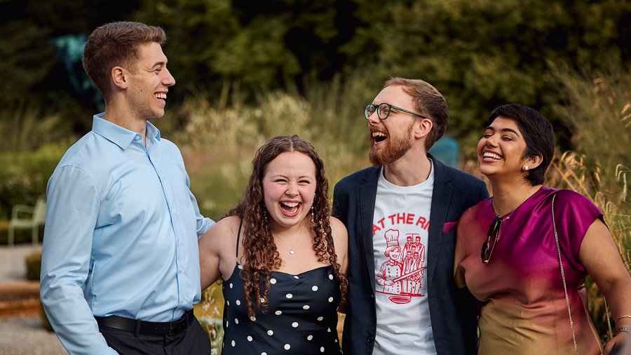 a group of four individuals laughing with each other outside