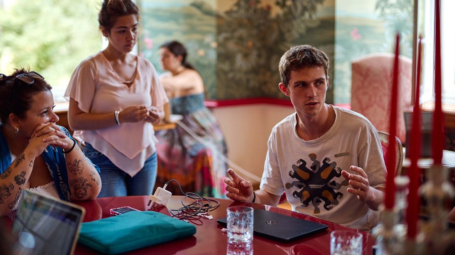 A man sits in the Red Salon talking to someone off-camera.