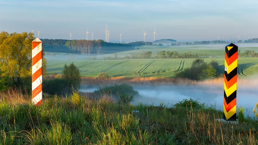 landscape with two border posts, one with the german flag and one with the polish flag