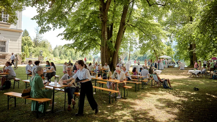 an outdoor green space is filled with picnic tables and people