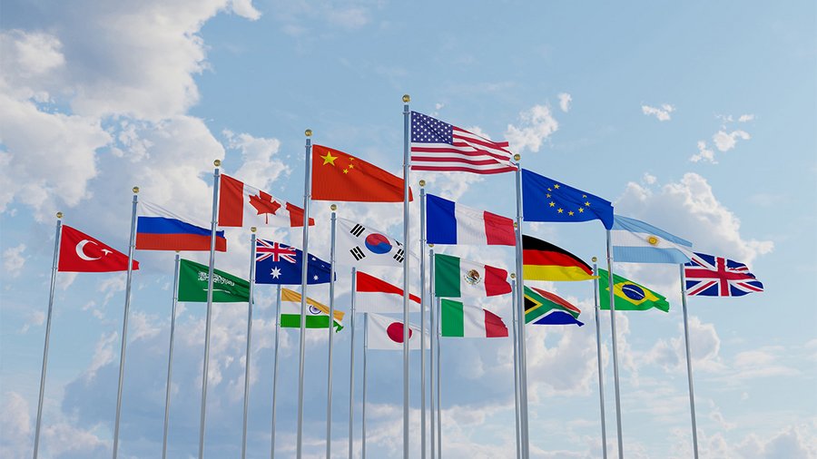 A group of national flags representing the G20 members against a blue background.