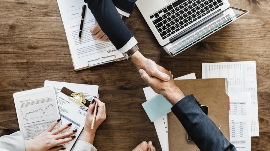 Two people shake hands during a business meeting
