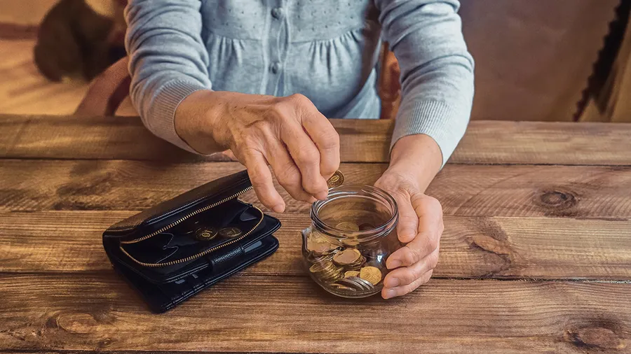 A man empties a jar of coins onto a table.